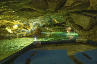 View from a boat of the impressively illuminated interior of a cave with running water, Wimsener