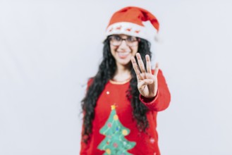 Happy girl in Christmas hat counting number FOUR, isolated. Smiling girl in Christmas sweater