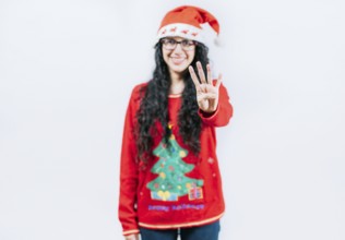 Smiling girl in Christmas sweater counting number 4. Happy girl in Christmas hat counting number