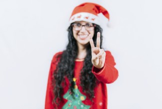 Happy girl in Christmas hat counting number TWO, isolated. Smiling girl in Christmas sweater