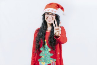 Happy girl in Christmas hat counting number THREE, isolated. Smiling girl in Christmas sweater