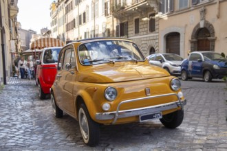 A yellow Fiat 500 is parked in an alley in central Rome