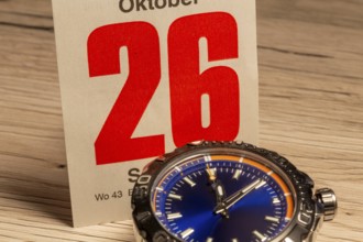 Wintertime 2025 time change: Close-up of a wristwatch and a sheet of a tear-off calendar showing