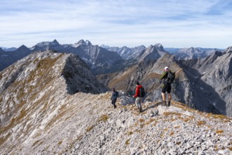 Hikers on the summit ridge of the Gamsjoch, behind rock faces of the Laliderer Spitze, eastern