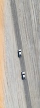Aerial view, top-down view, two off-road cars driving on a road in arid countryside, Botswana