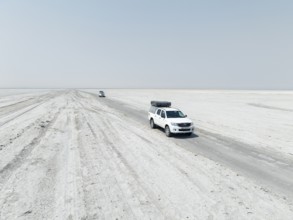 Aerial view, two off-road cars driving on a salt pan, arid landscape, Botswana