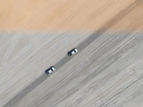 Aerial view, top-down view, two off-road cars driving on a road in arid countryside, Botswana