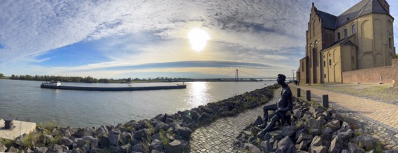 Photo with melancholy mood of bronze sculpture Poortekerl looking at Rhine waiting for ship to