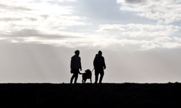 Couple with dog walking across a dike on the Baltic Sea, Fehmarn, 16.10.2025, Fehmarn,