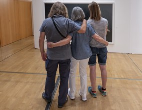 Three visitors look at a painting in an exhibition, Bavaria, Germany