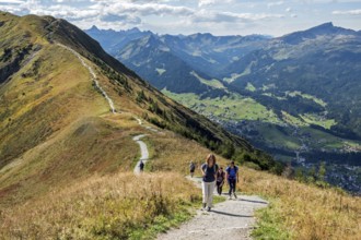 Hikers on the Fellhorn ridge hiking trail, behind Kleinwalsertal with mountains of the Allgäu Alps,