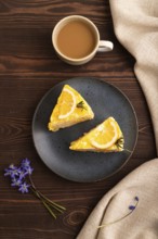 Lemon cake on brown wooden background and linen textile, cup of coffee, top view, flat lay, close