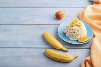White ?ottage cheese, Curd, with Banana on blue wooden background and orange textile, side view,