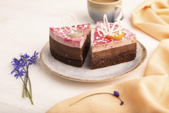 Chocolate cake on white wooden background and orange linen textile, cup of coffee, side view, close