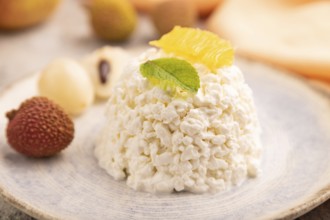 White ?ottage cheese, Curd, with orange and lychee on brown concrete background and orange textile,