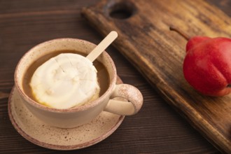 ?hocolate Ice cream in white glaze, cup of coffee, on brown wooden background, side view, close up,