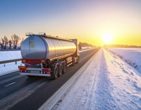 Petrol cargo truck lorry tanker driving on highway hauling oil products at sunrise, wide snowy