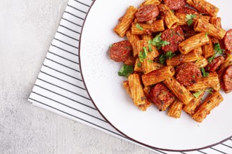 Rigatoni pasta with spicy sausage, and rich tomato sauce served, on a white plate, homemade