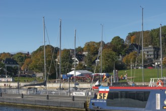 Kiel harbour, Kiellinie waterfront, Reventlou pier, restaurant, ferry, trees in autumn colors, blue