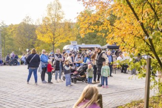 Families and children enjoy an outdoor picnic under colorful trees on an autumn day, Urschelherbst