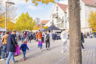 Families with children enjoy an autumnal day on a busy street with yellow trees, Urschelherbst