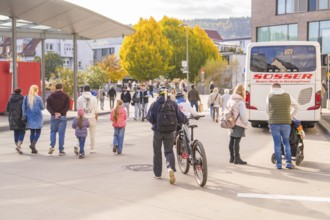 Busy scene at a bus stop, people on the move, a cyclist pushes his bike, Urschelherbst street
