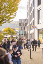 A busy street scene in a city, people walking near shops and buildings, Urschelherbst street