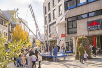 People enjoy activities on bungee trampolines in front of municipal shops and a pharmacy,