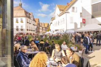 People sit in a street café in an old town under sunny skies. Busyness and convivial atmosphere