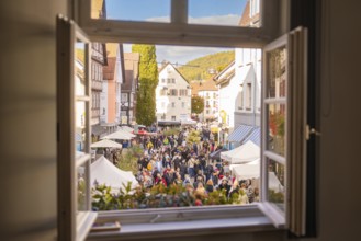 View through a window of a lively crowd and market stalls in a picturesque old town, Urschelherbst