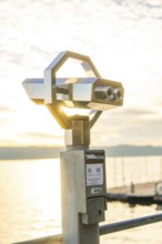 Modern metal binoculars with a view of the lake at sunrise, Überlingen, Lake Constance, Germany