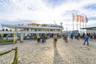 People at the harbor in sunny weather and blue sky, surrounded by flags and ships, Überlingen, Lake
