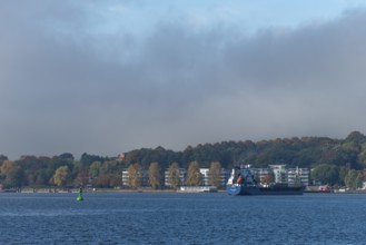Kiel Fjord, Holtenau district, Kiel, modern apartments on the river bank, cargo ship, hillside,