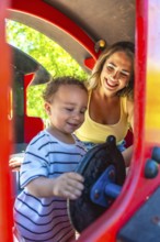Mother and toddler having fun playing on a playground train ride, enjoying quality time together on