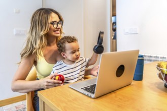 Mother and son sharing a moment of connection while using a laptop and headphones in their modern