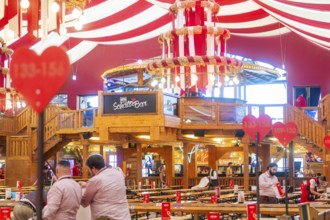 Interior view of a festively decorated beer tent with heart decorations and a bar in the centre,