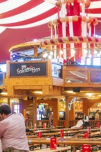 Bar area in a festively decorated beer tent with red ceilings and wooden elements, Volksfest