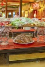 Close-up of beer mugs and packaged food on red tables in the marquee, Cannstatter Wasen folk