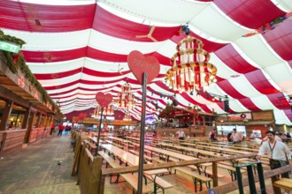 Cosy beer tent with red blankets, wooden benches and hearts as decoration, Volksfest Cannstatter