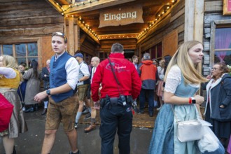 Visitors in traditional traditional costume leaving a wooden entrance at the Oktoberfest while