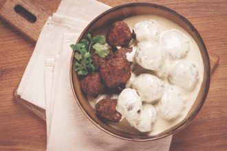 Swedish meatballs in cream sauce, plate on a wooden table, homemade, no people
