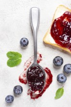 A spoon with blueberry jam, on a white table, breakfast, top view, homemade, no people