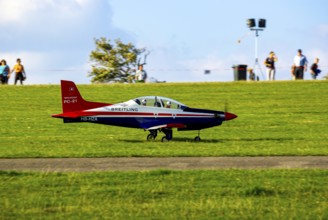 An RC model of a Pilatus PC-21 with advertising for the Swiss watch brand Breitling during a flight