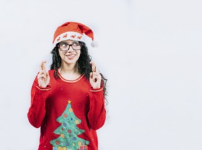 Young woman in Christmas sweater making a wish and crossing fingers. Beautiful girl in Christmas