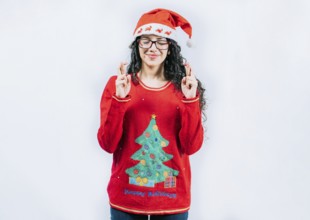 Beautiful girl in Christmas sweater making a wish isolated. Young woman in Christmas sweater making