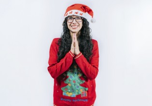 Supplicant girl in Christmas sweater making a wish, isolated. Young woman in a Christmas hat with