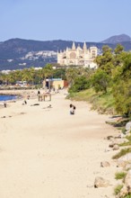 People on a sand beach by the Mediterranean Sea and the famous landmark Palma cathedral a sunny
