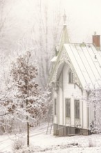 Winter day with snow and hoarfrost on the trees in the garden by an idyllic old beautiful white