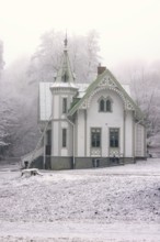 Old idyllic white wooden house with carpentry work a cold winter day with snow and frost,