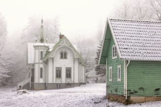 Old idyllic white wooden house with carpentry and a green garden shed on a cold winter day with